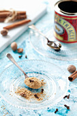 A gingerbread spice mixture on a spoon and a glass dish
