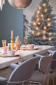 Weihnachtlich gedeckter Tisch, vor Wandteppich mit Lichterkette