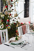 Festive place settings on dining table in front of Christmas tree