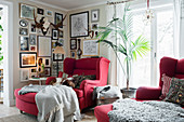 Red armchair below antlers and framed photos on walls