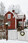 Rotes Schwedenhaus mit schneebedeckter Garten