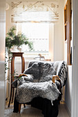 Grey sheepskin blanket on armchair in front of window
