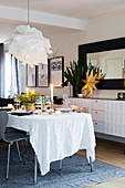 Festively set Christmas table next to sideboard and mirror