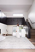 Elegante, minimalistische Halle mit Treppenaufgang, Frau in weißem Kleid