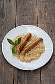 Soya sausages on sauerkraut with fresh laurel on a wooden background