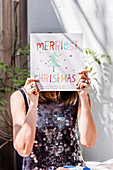 Woman holds Christmas greeting in front of her face