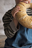 A boy eating sourdough bread with a blue apron