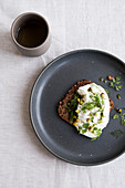 Sourdough bread with burrata and pistachio nuts on a dark plate with a cup of tea