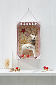 3D diorama of Christmas decorations in pink-painted fruit crate hung on wall