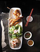 Various kebabs, lettuce, and shrimp salad on a platter (Asia)