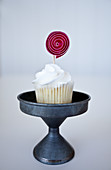 A mini vanilla cupcake with a pink cupcake topper