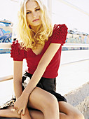 A blonde woman wearing a red blouse and brown shorts