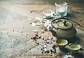 Asiatisches Teestilleben mit Teekanne, Teeschalen, Kerzen und Blüten