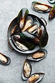 Raw kiwi mussels on textured light colored background