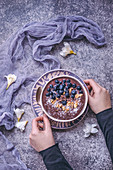 Frau isst Smoothie Bowl mit Blaubeeren, Walnüssen, Kakaonibs und Kokos