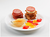 Crackers with sausage slices and cheese served with applesauce and wine gums