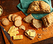 Soda bread and soda crackers with butter and cheese on a wooden chopping board