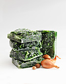 Creamed spinach, frozen in blocks against a white background
