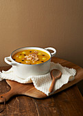 Pumpkin soup in a pot on a rustic wooden table