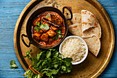Chicken tikka masala spicy curry meat food with rice and naan bread on copper tray close-up