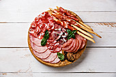 Cold meat plate Italian snacks food with ham, prosciutto, salami, pork chops, sausage and grissini bread sticks on wooden background