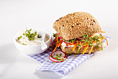 A wholemeal roll with a cream cheese and egg spread, radishes and cress