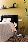 Yellow wall behind bed in bedroom
