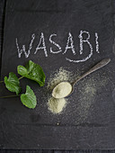 Wasabipulver und Wasabiblätter auf Schiefertafel mit Schriftzug