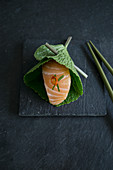 Nigiri sushi with salmon in a fresh wasabi leaf