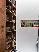 Glasses and crockery on wooden shelves next to niche in wall