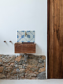 Wooden sink mounted on wall above stone wall