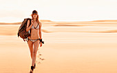 Junge Frau mit Rucksack im Bikini in der Wüste