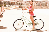 A young woman wearing a top and pink short with a bike