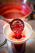 Lingon berry jam being made, jam being poured into a funnel