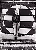 A blonde woman wearing a black blazer and jeans on an industrial site (black-and-white shot)