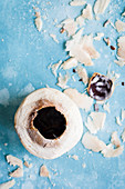 Frische Kokosnuss mit abgeriebener Kokosschale auf blauem Untergrund (Aufsicht)