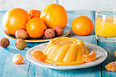 Mango orange pudding on white plate with fruits on wooden table