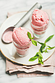 Strawberry yogurt ice cream in glasses over light grey marble table background