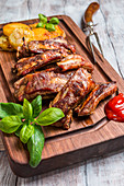 Delicious Grilled Pork Rib and Fried Potato Wedges with Sauce on wooden cutting board, white wooden background