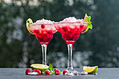 Margarita cocktail with lime and raspberries on nature background