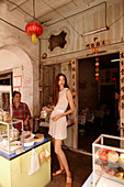 A young woman wearing a white mini dress at an oriental food stand