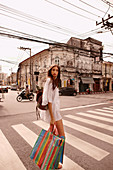 Junge Frau in weißem Tunikakleid mit Einkaufstasche