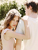 A young woman wearing a crown of flowers leaning on a young man