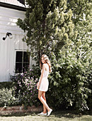 A young woman in a garden wearing a white playsuit