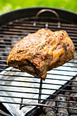 Spiced pork collar on a BBQ for making pulled pork