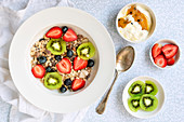 Müsli mit Erdbeeren, Blaubeeren und Kiwi dazu Passionsfruchtjoghurt (Aufsicht)