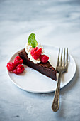 Dark chocolate cake with fresh whipped cream, fresh berries on white plates