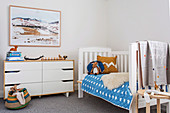 Bed and chest of drawers in the children's room in natural tones with blue accents