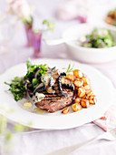 A beef steak with mushrooms, garlic butter, salad, vegetables and potatoes