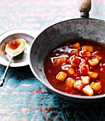 Sweet and sour sauce with pineapple, chillies and carrots in a wok